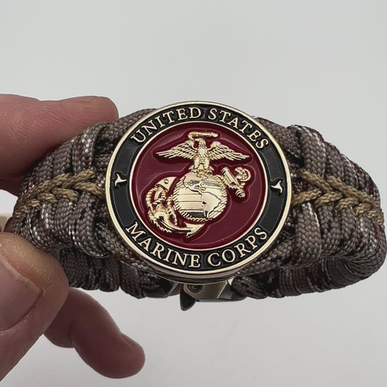 Thick, rigid and comfortable braided United States Marine Corps bracelet featuring a 24K gold plated USMC Eagle Globe and Anchor medallion, a gold Cobra style tactical buckle and woven with Desert Camo 550 paracord.