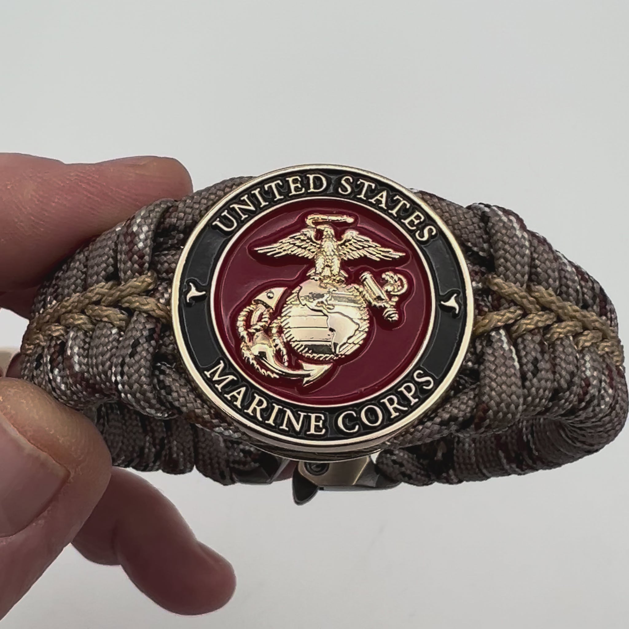 Thick, rigid and comfortable braided United States Marine Corps bracelet featuring a 24K gold plated USMC Eagle Globe and Anchor medallion, a gold Cobra style tactical buckle and woven with Desert Camo 550 paracord.