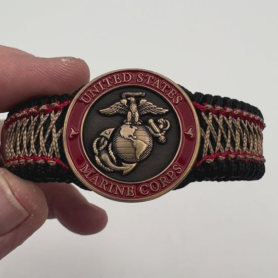 Thin, medium width, flexible and comfortable braided United States Marine Corps bracelet featuring a 24K antique gold plated USMC Eagle Globe and Anchor medallion, a black Cobra style tactical buckle and woven with black Type-1 paracord and Imperial Red and Gold nano cord.