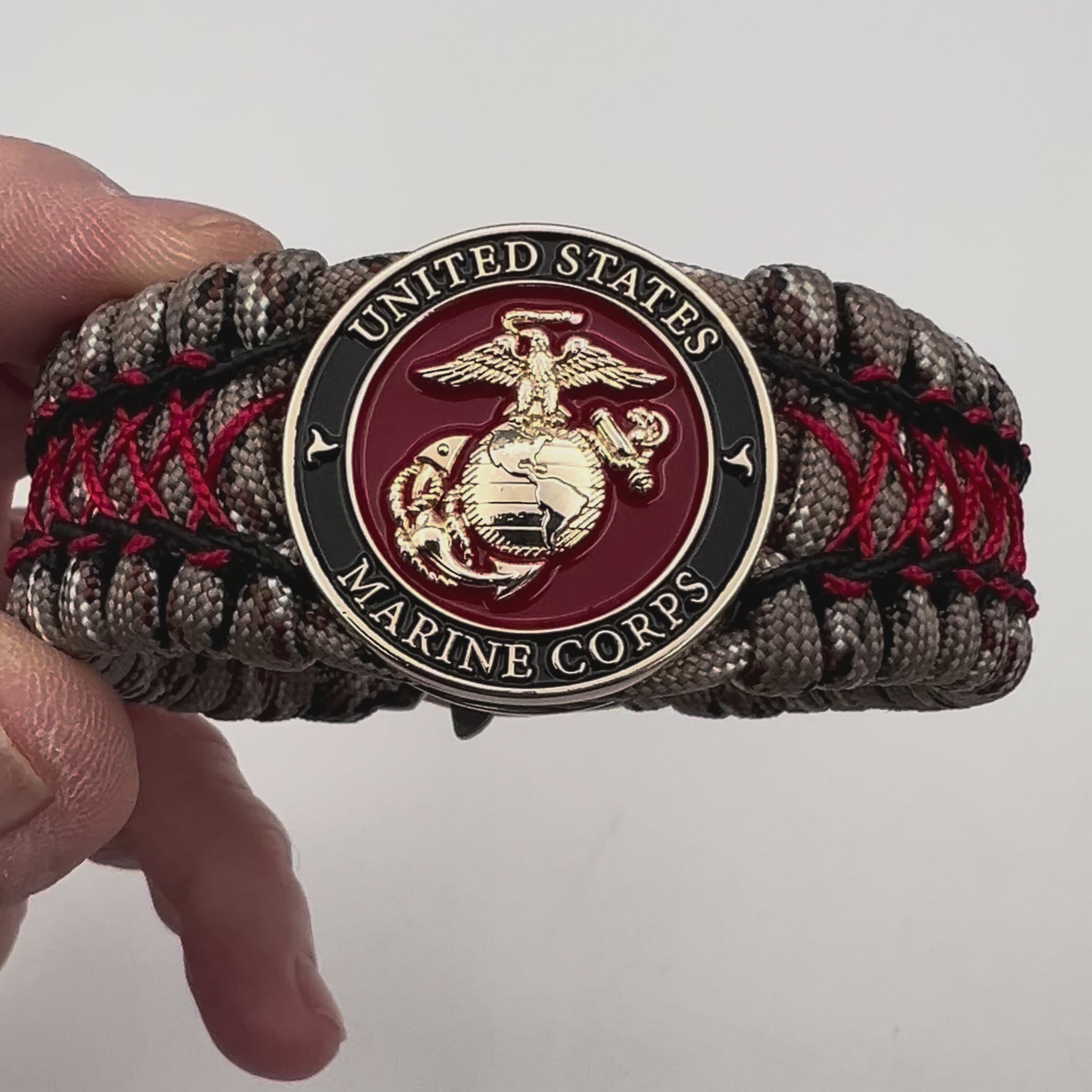 Thick, wide, rigid and comfortable braided United States Marine Corps bracelet featuring a 24K gold plated USMC Eagle Globe and Anchor medallion, a gold Cobra style tactical buckle and woven with Desert Camo 550 paracord, black micro cord and Imperial Red nano cord.