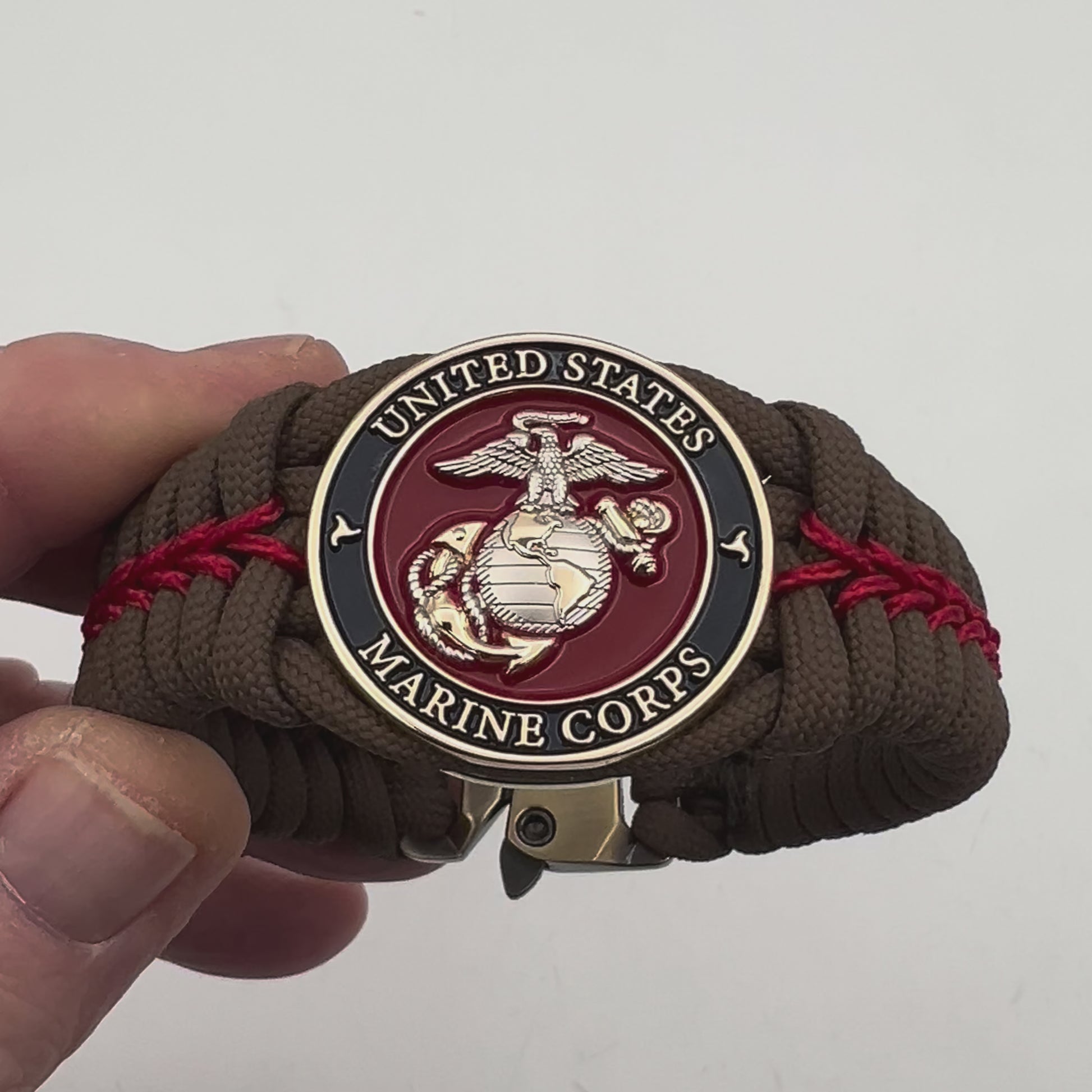 Thick, semi-rigid and comfortable braided United States Marine Corps bracelet featuring a 24K gold and silver plated USMC officer Eagle Globe and Anchor medallion, a Cobra style tactical buckle and woven with Coyote brown 550 and Imperial red micro paracord.