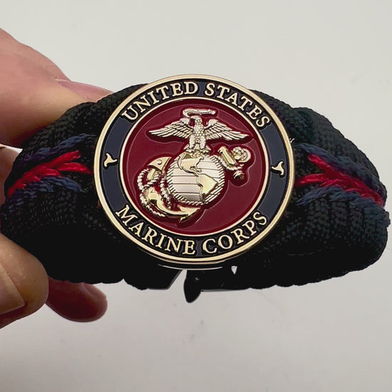 Thick, semi-rigid and comfortable braided United States Marine Corps bracelet featuring a 24K gold and silver plated USMC officer Eagle Globe and Anchor medallion, a black Cobra style tactical buckle and woven with Navy blue, Imperial red and black paracord.