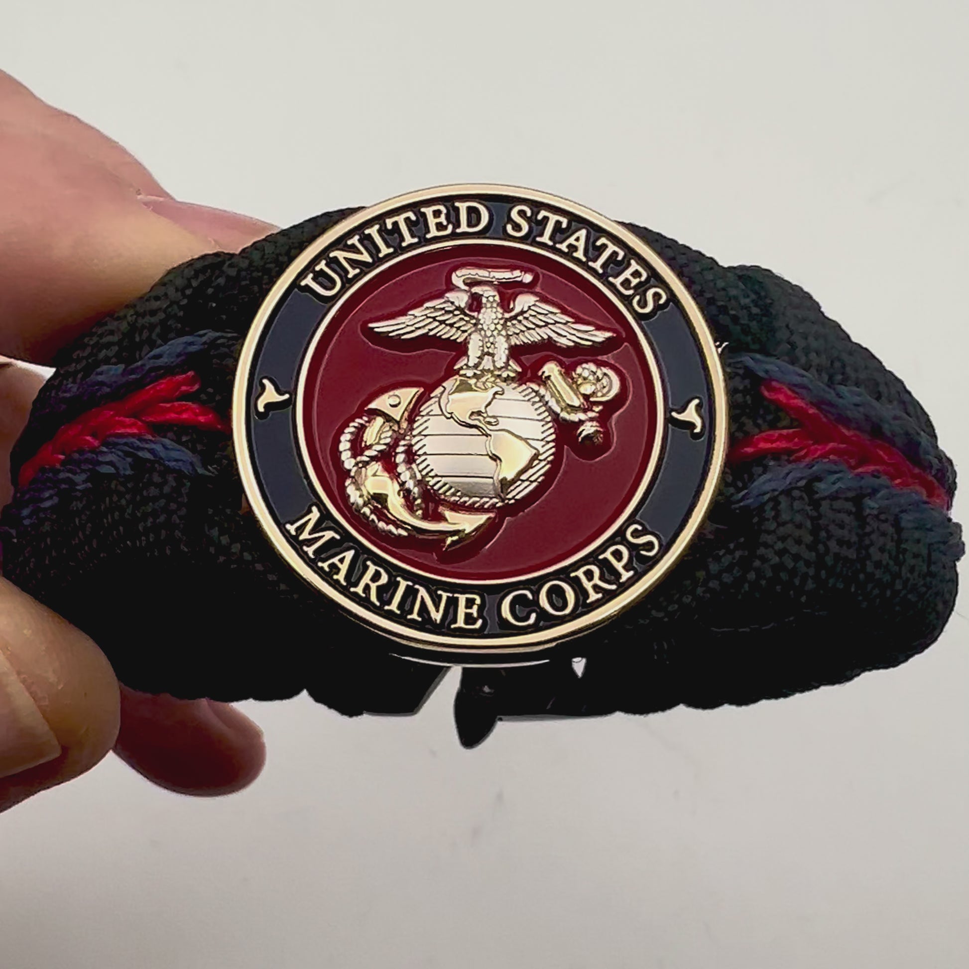 Thick, semi-rigid and comfortable braided United States Marine Corps bracelet featuring a 24K gold and silver plated USMC officer Eagle Globe and Anchor medallion, a black Cobra style tactical buckle and woven with Navy blue, Imperial red and black paracord.