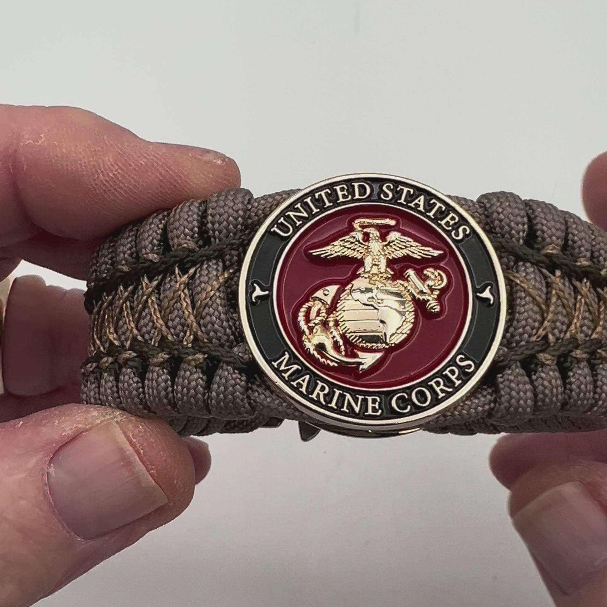 Thick, wide, rigid and comfortable braided United States Marine Corps bracelet featuring a 24K gold plated USMC Eagle Globe and Anchor medallion, a gold Cobra style tactical buckle and woven with tan 550 paracord and olive drab micro and tan nano cord.