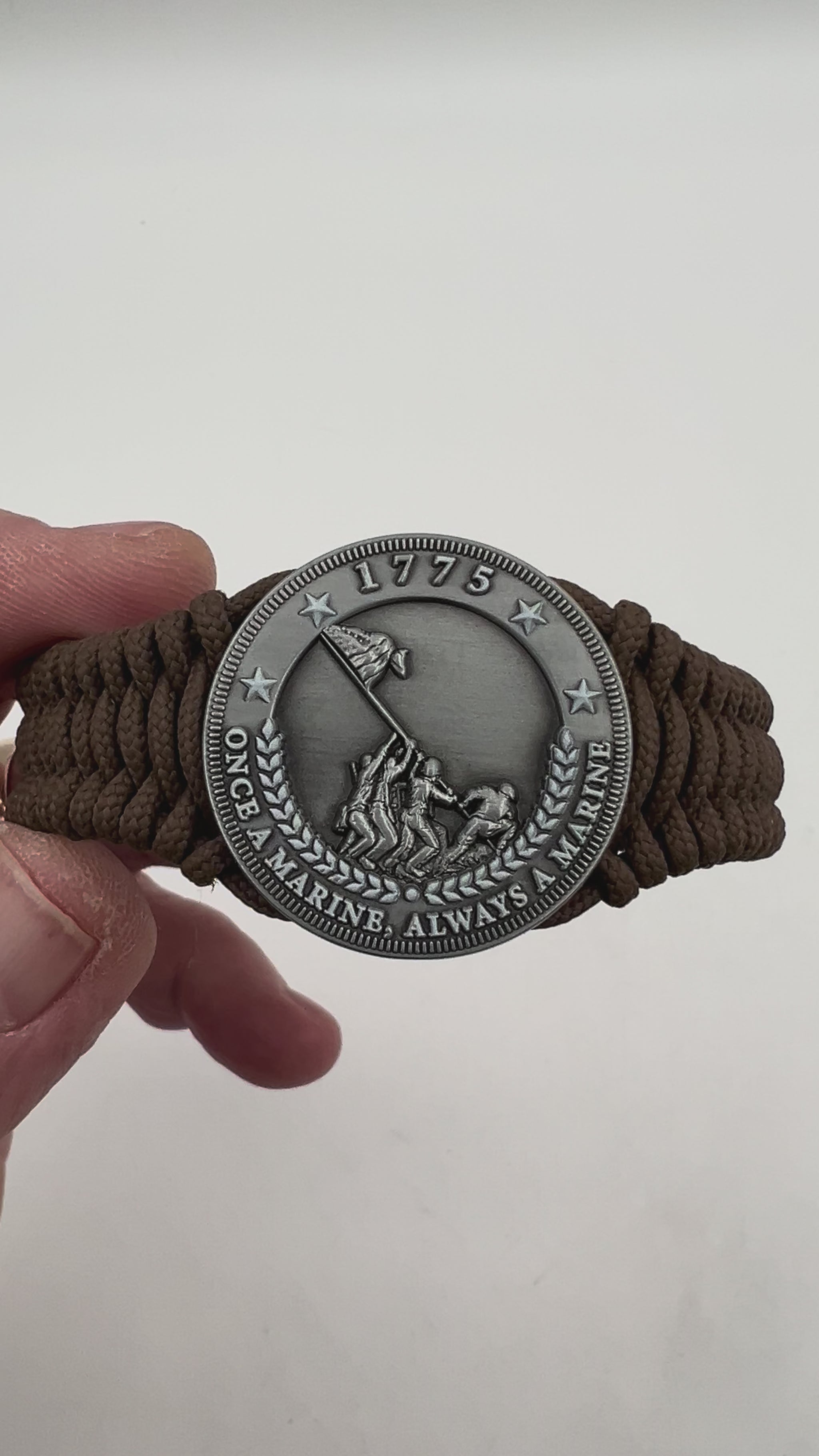 Thin, narrow, flexible and comfortable braided United States Marine Corps Iwo Jima bracelet featuring an antique silver plated Iwo Jima flag raising medallion, a silver Cobra style tactical buckle and woven with Coyote Brown type-1 paracord.