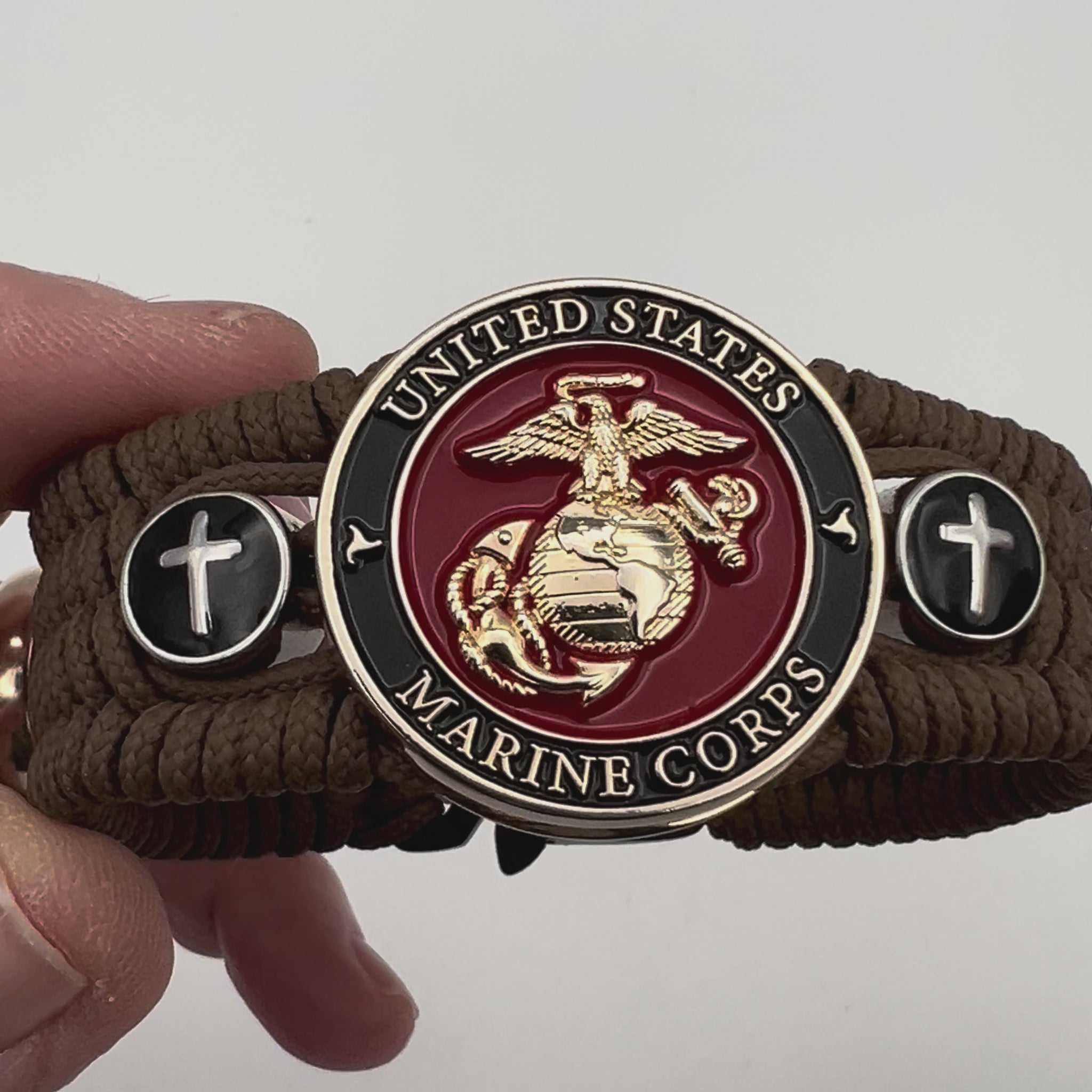 Thin, medium width, flexible and comfortable braided United States Marine Corps bracelet featuring a 24K gold plated USMC officer Eagle Globe and Anchor medallion, two Christian crosses, a black Cobra style tactical buckle and woven with Coyote Brown Type-1 paracord.