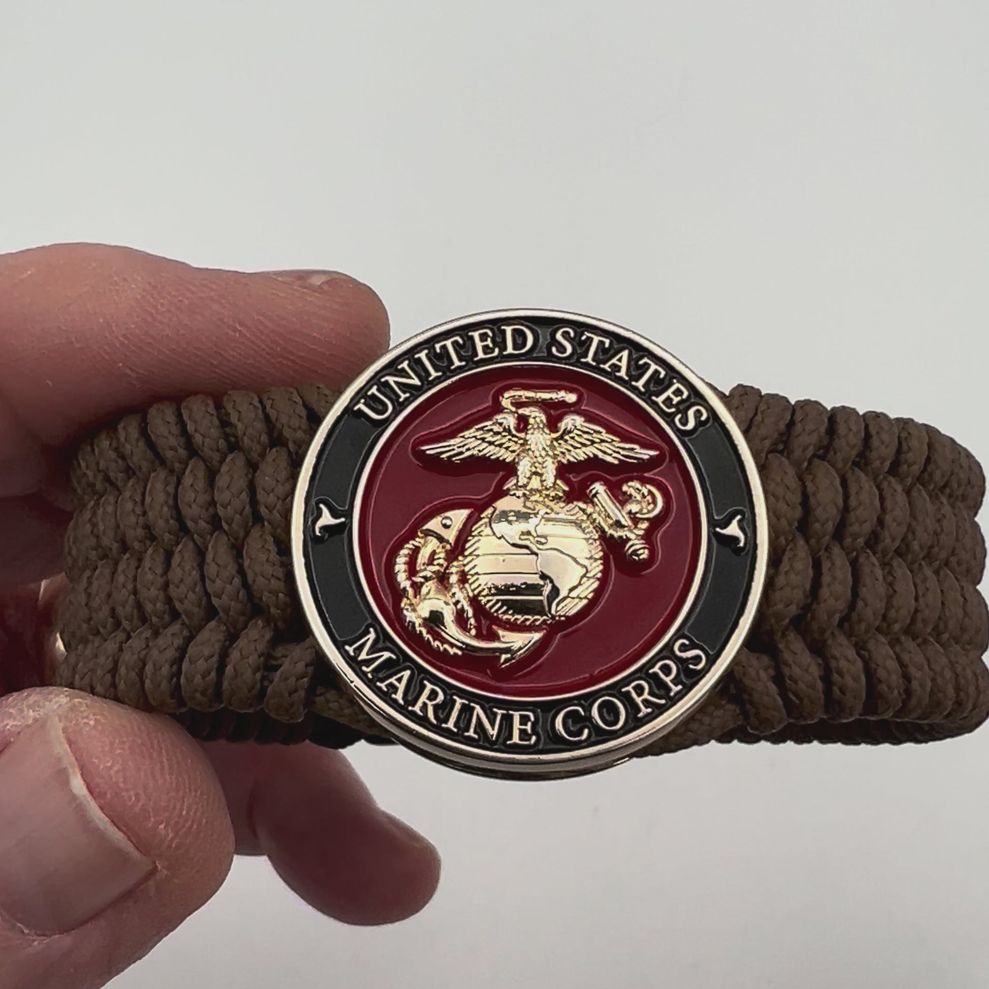 Thin, medium width, flexible and comfortable braided United States Marine Corps bracelet featuring a 24K gold plated USMC officer Eagle Globe and Anchor medallion, a gold Cobra style tactical buckle and woven with Coyote Brown Type-1 paracord.