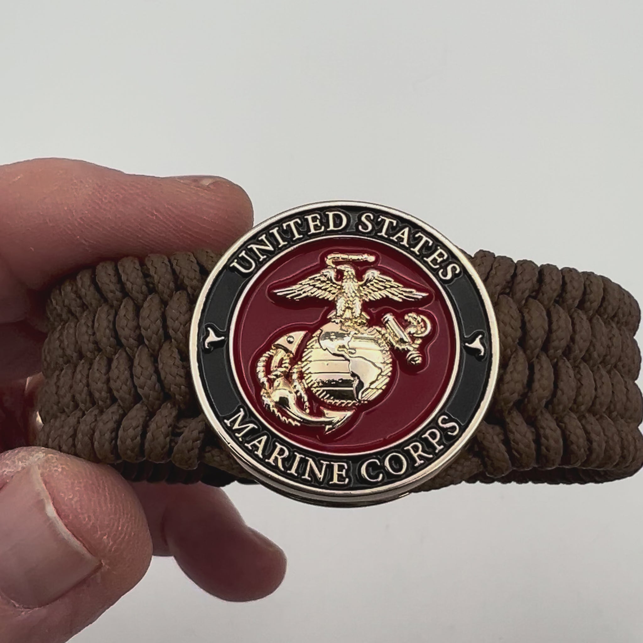 Thin, medium width, flexible and comfortable braided United States Marine Corps bracelet featuring a 24K gold plated USMC officer Eagle Globe and Anchor medallion, a gold Cobra style tactical buckle and woven with Coyote Brown Type-1 paracord.