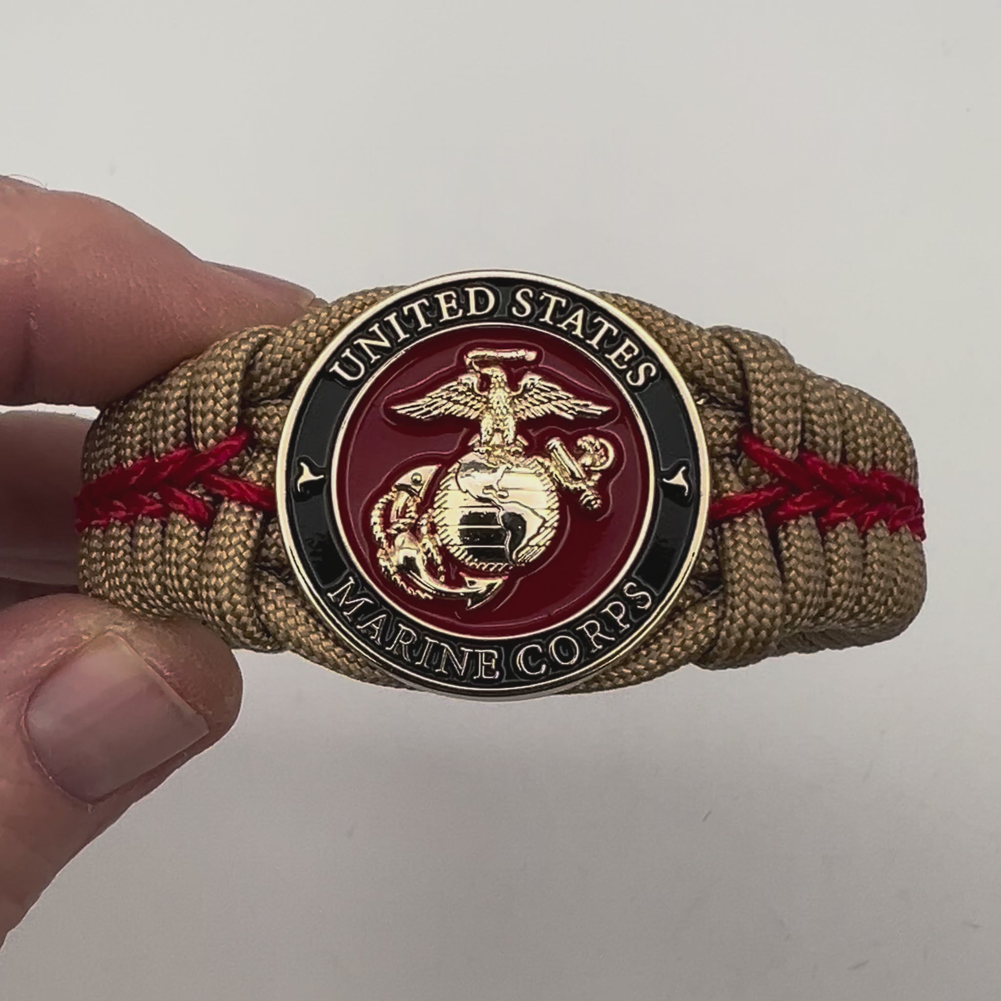 Thick, semi-rigid and comfortable braided United States Marine Corps bracelet featuring a 24K gold plated USMC officer Eagle Globe and Anchor medallion, a gold Cobra style tactical buckle and woven with gold 550 paracord and Imperial Red micro cord.