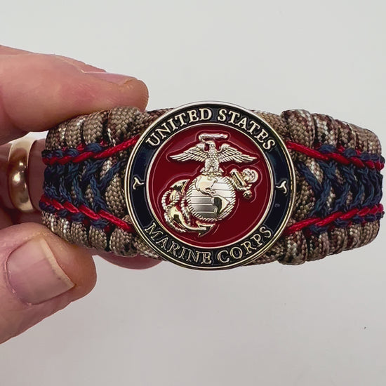 Thick and comfortable braided United States Marine Corps bracelet featuring a 24K gold and silver plated USMC officer Eagle Globe and Anchor medallion, a gold Cobra style tactical buckle and woven with Desert Camo 550 paracord and Imperial Red and Navy Blue micro cord.