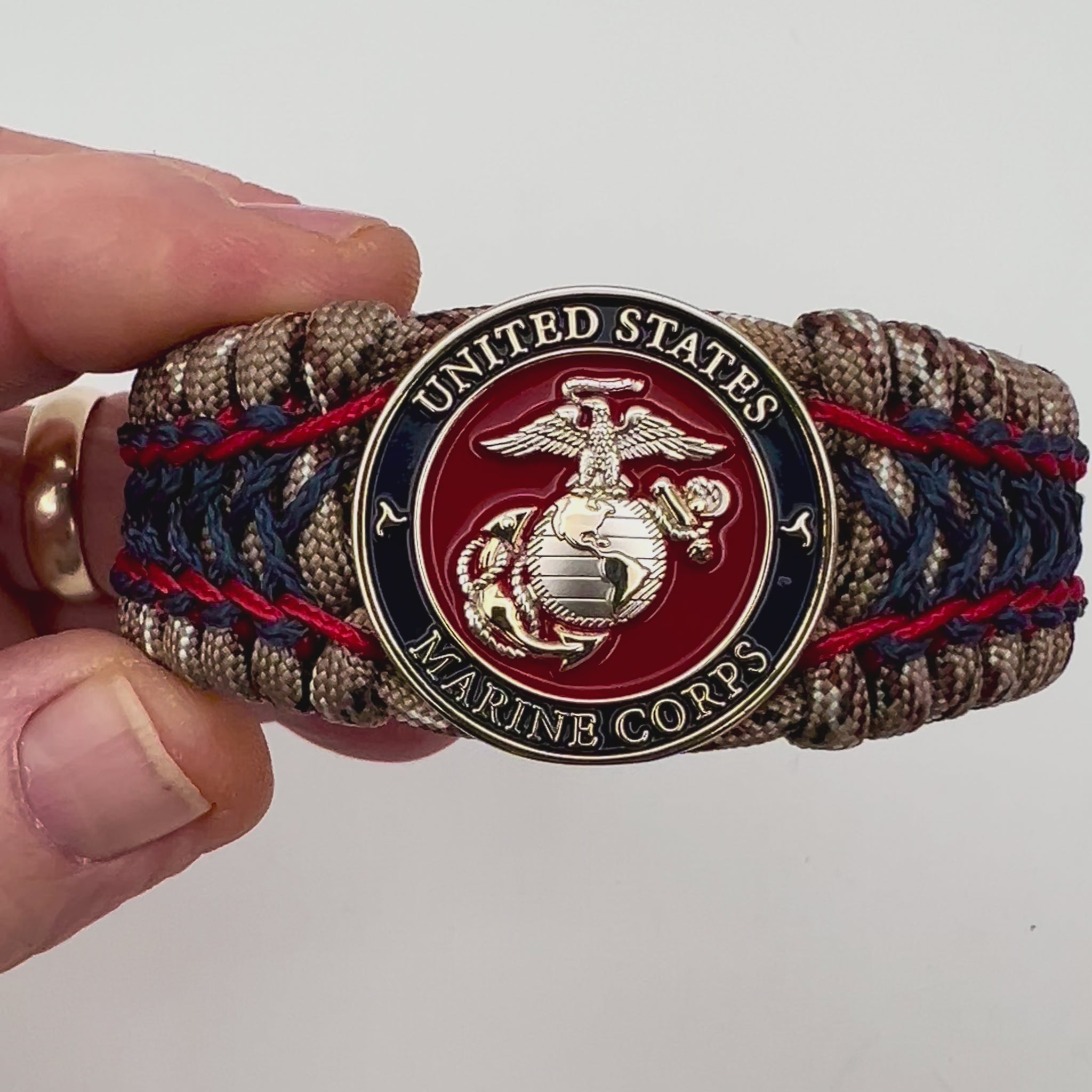 Thick and comfortable braided United States Marine Corps bracelet featuring a 24K gold and silver plated USMC officer Eagle Globe and Anchor medallion, a gold Cobra style tactical buckle and woven with Desert Camo 550 paracord and Imperial Red and Navy Blue micro cord.