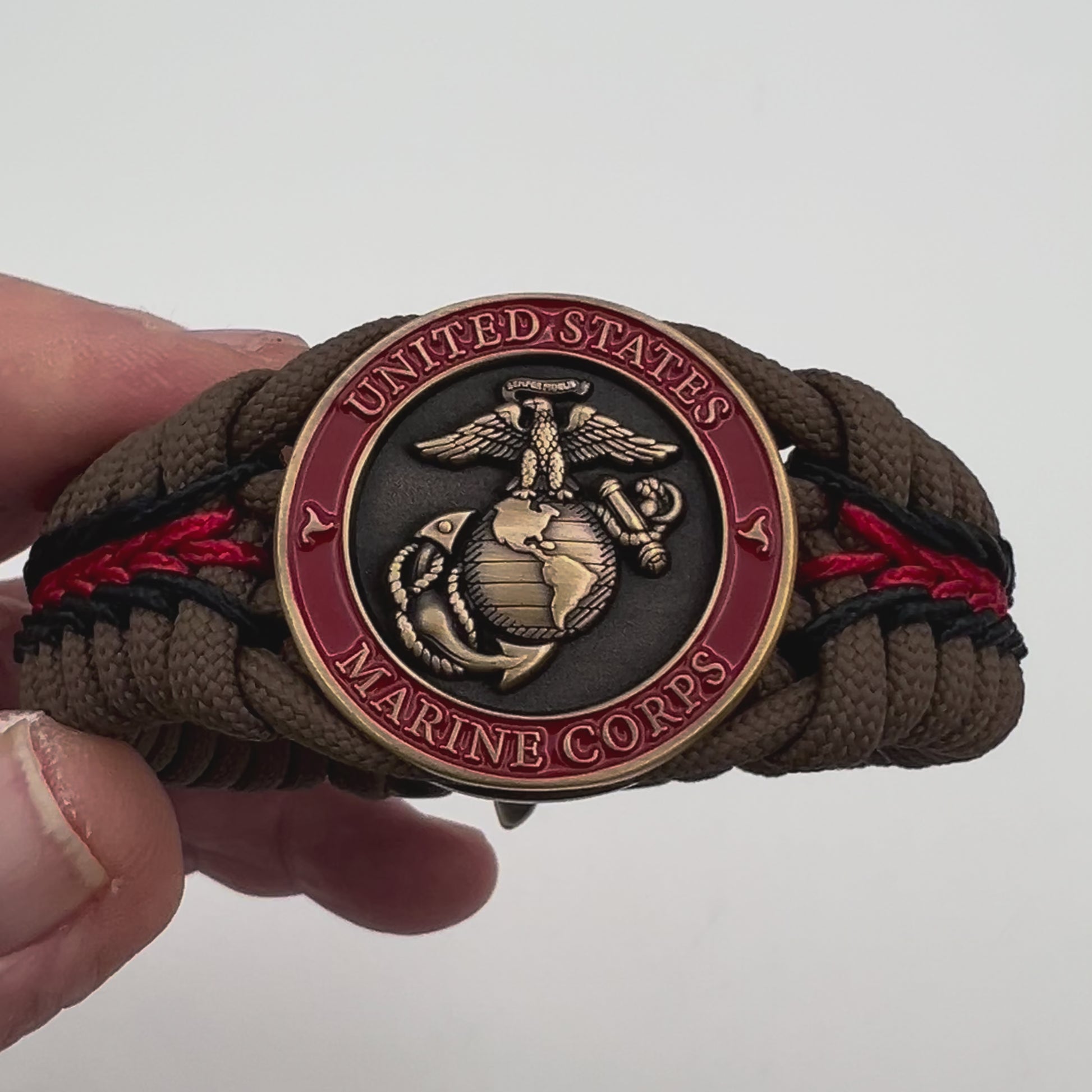 Thick, medium width, rigid and comfortable braided United States Marine Corps bracelet featuring a 24K antique gold plated USMC Eagle Globe and Anchor medallion, a gold Cobra style tactical buckle and woven with Coyote Brown 550 paracord and Imperial Red and Black micro cord.