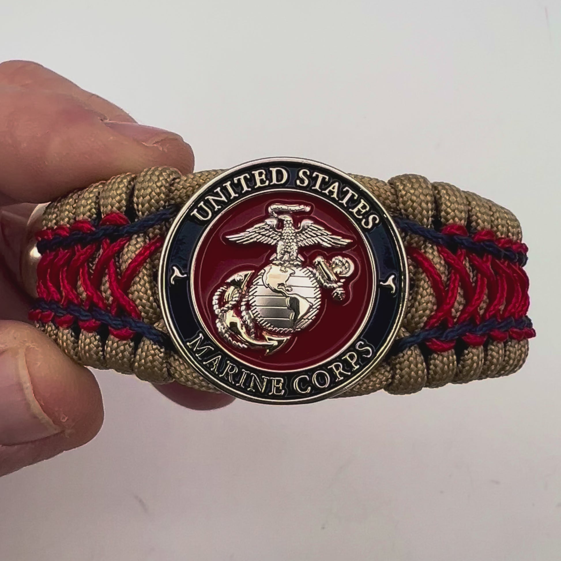 Thick and comfortable braided United States Marine Corps bracelet featuring a 24K gold and silver plated USMC officer Eagle Globe and Anchor medallion, a gold Cobra style tactical buckle and woven with gold 550 paracord and Imperial Red and Navy Blue micro cord.