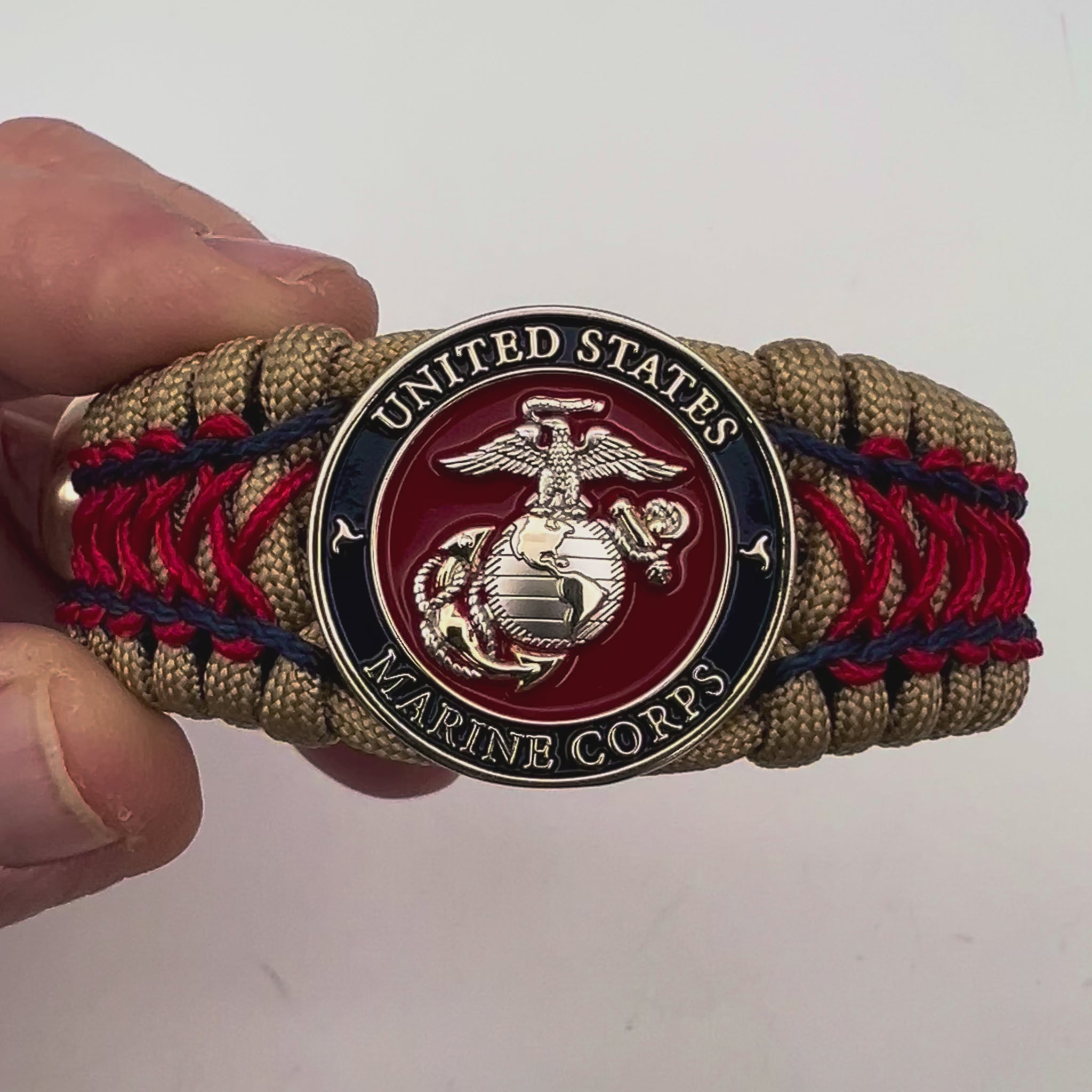 Thick and comfortable braided United States Marine Corps bracelet featuring a 24K gold and silver plated USMC officer Eagle Globe and Anchor medallion, a gold Cobra style tactical buckle and woven with gold 550 paracord and Imperial Red and Navy Blue micro cord.