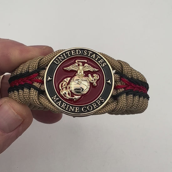 Thick, rigid and comfortable braided United States Marine Corps bracelet featuring a 24K gold plated USMC officer Eagle Globe and Anchor medallion, a gold Cobra style tactical buckle and woven with gold 550 paracord and Imperial Red and black micro cord.