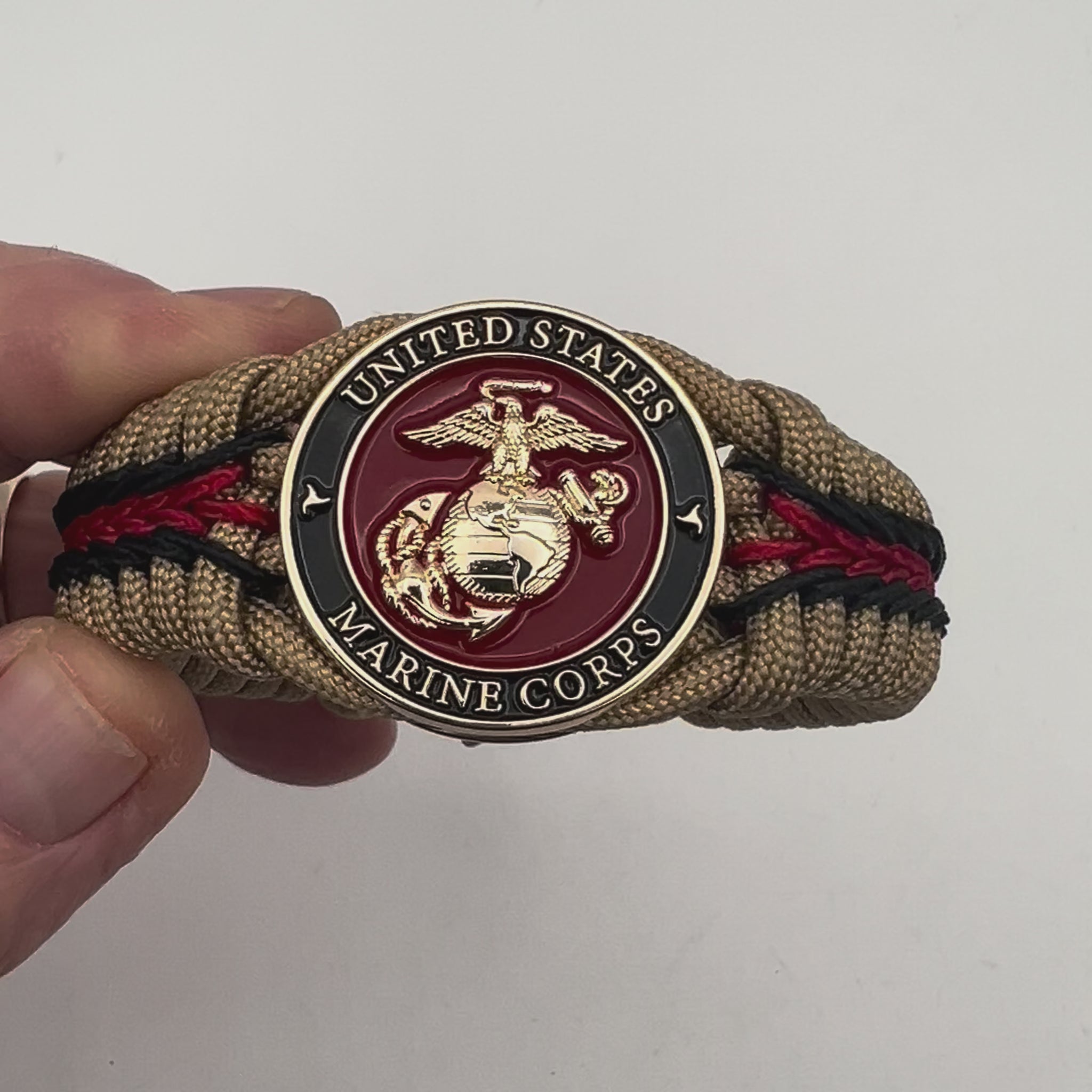 Thick, rigid and comfortable braided United States Marine Corps bracelet featuring a 24K gold plated USMC officer Eagle Globe and Anchor medallion, a gold Cobra style tactical buckle and woven with gold 550 paracord and Imperial Red and black micro cord.