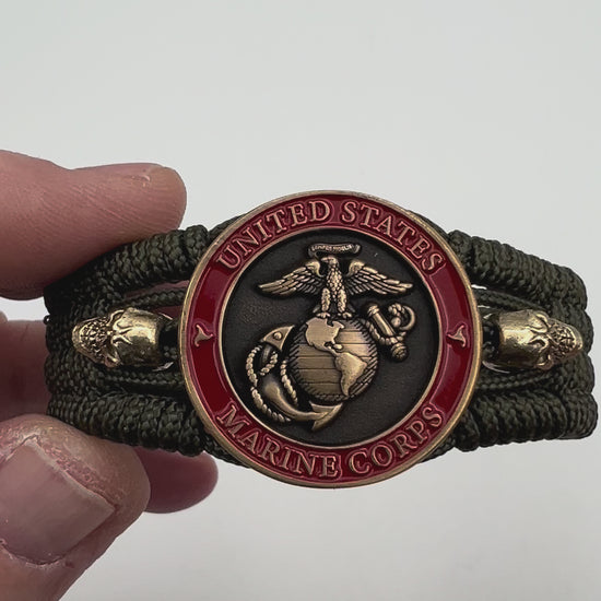 Thin, medium width, flexible and comfortable braided United States Marine Corps bracelet featuring a 24K antique gold plated USMC officer Eagle Globe and Anchor medallion, two gold plated skulls, a gold Cobra style tactical buckle and woven with Olive Drab Type-1 paracord.